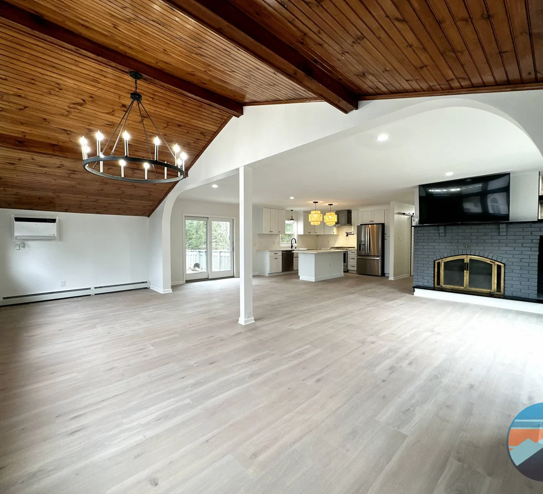 Reconstructed living space with a vaulted wood ceiling, new flooring, and restored fireplace